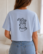 Sip Happens Crop Tee in Sky Blue am Model – Rückenprint gestapelte Kaffeetassen